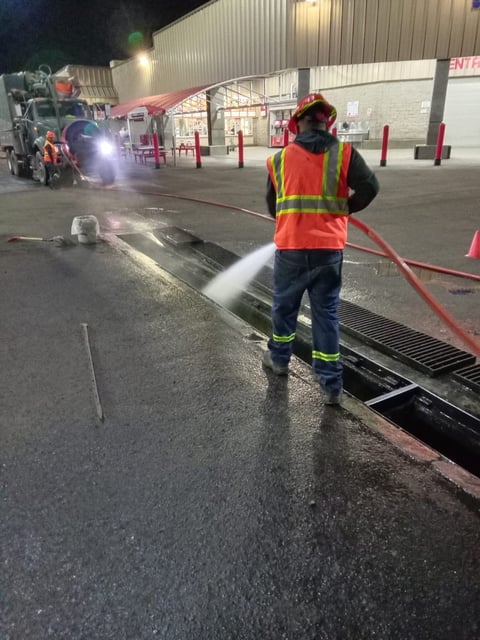 Trabajador rociando agua en estacionamiento durante mantenimiento nocturno